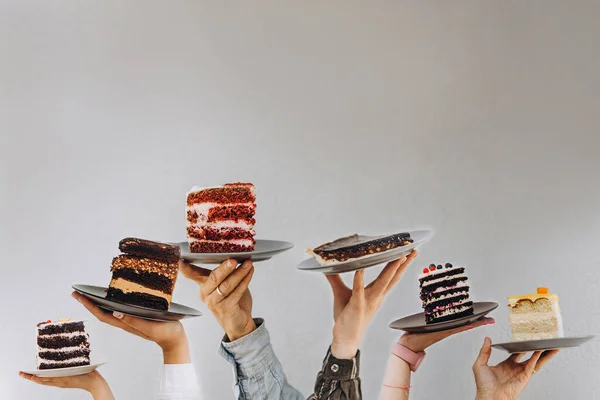 デザート付きのカフェやパン屋のコンセプト 人々の手に異なるケーキを持つプレート あなたのテキストのための場所 — ストック写真