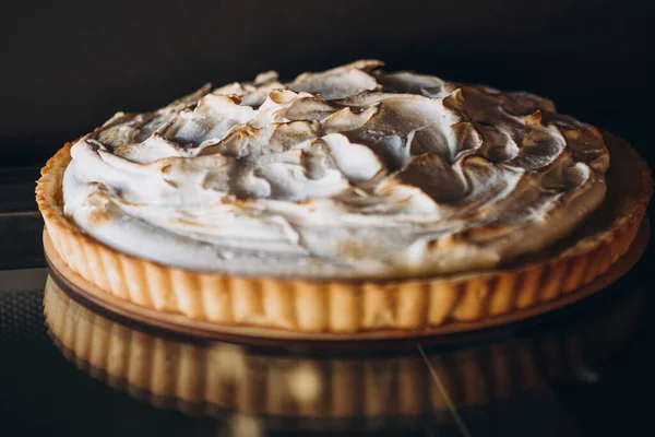 Tasty lemon meringue pie. Traditional french sweet pastry tart. Delicious, appetizing, homemade dessert with lemon cream. Copy space, closeup. Selective focus. Black background. Toned