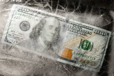 Yeni 100 dolarlık banknot buz tabakasının altında, küresel ekonomik kriz konsepti veya doların dünya piyasasına düşüşü