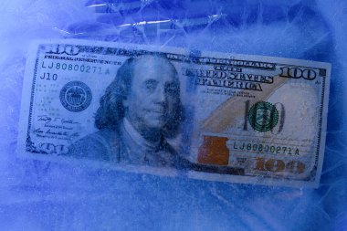 Yeni 100 dolarlık banknot buz tabakasının altında, küresel ekonomik kriz konsepti veya doların dünya piyasasına düşüşü