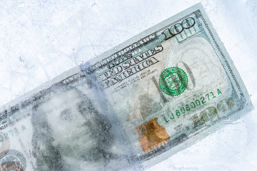 New $ 100 bill frozen under a layer of ice, the concept of the global financial crisis or the fall of the dollar on the world market