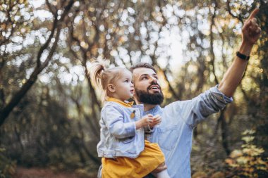 Sonbahar parkında tatlı kızlarıyla birlikte güneşli havanın tadını çıkaran şık hippilerden oluşan genç mutlu bir aile.