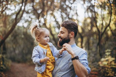 Sonbahar parkında tatlı kızlarıyla birlikte güneşli havanın tadını çıkaran şık hippilerden oluşan genç mutlu bir aile.