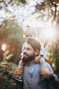 Sonbahar parkında tatlı kızlarıyla birlikte güneşli havanın tadını çıkaran şık hippilerden oluşan genç mutlu bir aile.
