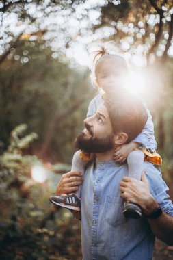 Sonbahar parkında tatlı kızlarıyla birlikte güneşli havanın tadını çıkaran şık hippilerden oluşan genç mutlu bir aile.