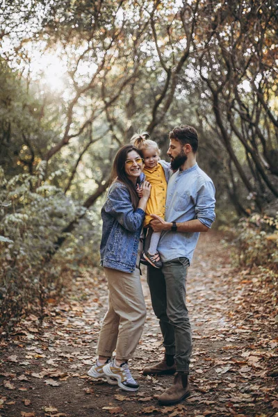 秋の公園を歩いている若いスタイリッシュなヒップスターの幸せな家族と彼らの甘い娘は晴れた天候を楽しんで — ストック写真