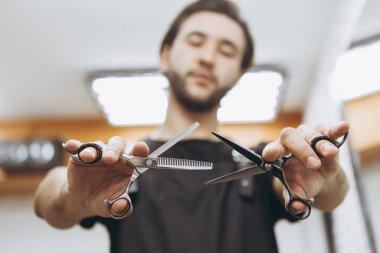 Şık ve çekici sakallı bir berber, kollarını uzattığı zaman profesyonel saç makası tutar. Makasa odaklan sen. Berber dükkanları, güzellik salonları ve kuaförler için konsept