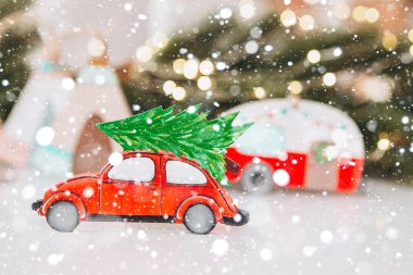 Kış arka planında Noel ağacı olan neşeli çelenklerle dolu bir oyuncak araba. Metnin için bayram kartı, afiş ya da yer kavramı