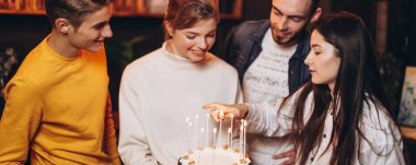 Arkadaşlar sevgililerinin doğum günü pastası için mum yakarlar.