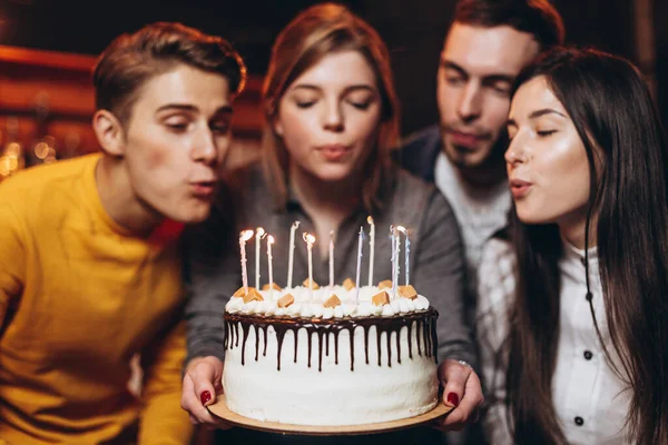 Surprise for her. Group of happy people celebrating birthday party with friends and smiling during party. Smiling attractive girl holding a cake in her hands