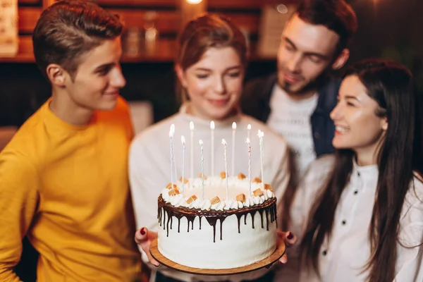 attractive teenage girl celebrating her birthday with cake together with best friends who decided to surprise her and unexpectedly greet her at a holiday party in home