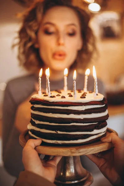 年轻迷人的金发姑娘带着华丽的模特微笑捧着蛋糕 一个快乐的生日女孩在意想不到的礼物中的情感 自制的蛋糕 点着蜡烛 有选择性地聚焦 噪音效果 — 图库照片