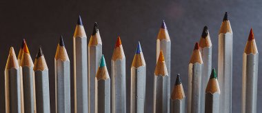 Koyu bir zemin üzerinde farklı yüksekliklere sahip ve birbirinden farklı renkte birçok kalemler vardır.