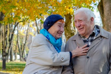 Mutlu yaşlı çift sonbahar parkında dinleniyor.