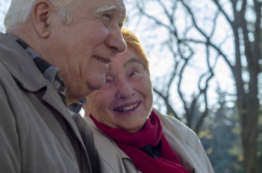 Güneşli bir günde parkta gülümseyen yaşlı, mutlu beyaz bir çift. Kıdemli çift parkta sonbahar zamanı dinleniyor. Sağlık hizmetleri yaşam tarzı yaşlılar emekliliği Sevgililer Günü konsepti
