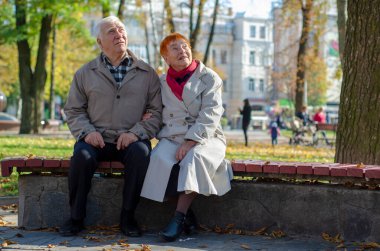 Yaşlı yaşlı çift parkta dinleniyor ve yukarı bakıyor. Boşluğu kopyala