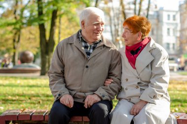 Yaşlı çift gülüyor. Parktaki kadın ve erkek yan yana otururlar. Eski komik şakalar. Espri anlayışı. 