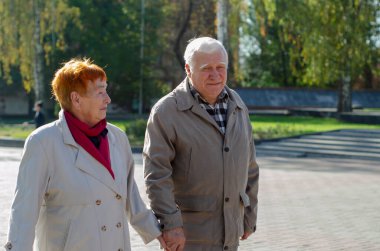 Büyüleyici yaşlı bir kadının yakın plan portresi. Kocasıyla sokak arkasındalar. Birbirine aşık iki yaşlı insan..