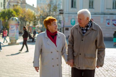 Büyüleyici yaşlı bir kadının yakın plan portresi. Kocasıyla sokak arkasındalar. Birbirine aşık iki yaşlı insan..