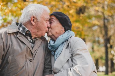 Sonbaharda öpüşen güzel bir son sınıf çifti. Birlikte uzun bir hayat yaşayan bir ailenin mutlu yaşlılığı. Uzayı kopyala Güzel yaşlı çift sonbaharda oturuyor..