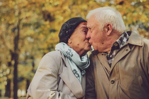 Love lives forever! Senior couple at home. Handsome old man and attractive old woman are hugging, kissing and enjoying spending time together.