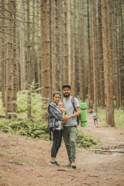 Çocukları olan aile gezgin ormana doğru yürürken