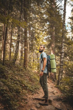 Ormanda dağın tepesine tırmanırken turist çantalı havalı ve şık sakallı bir turist.