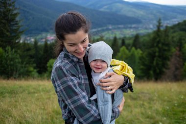 Anne ve bebeği bir kanguru sırt çantasında ya da dağlarda ve ormanlarda dolaşırken askıda.