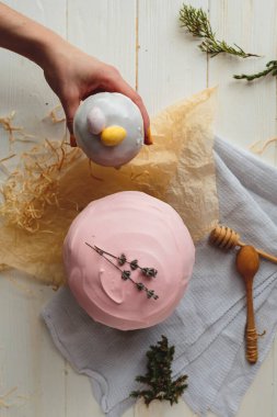 Paskalya arkaplanı, jöleli, çikolatalı ve yumurtalı bir paskalya ekmeği. Tebrik kartı, reklam, promosyon, poster, el ilanı, makale için resim. Karmaşık kompozisyon, güzel manzara, eller. Paskalya yemeğinin düz manzarası 