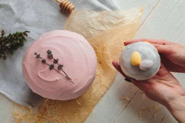 Paskalya arkaplanı, jöleli, çikolatalı ve yumurtalı bir paskalya ekmeği. Tebrik kartı, reklam, promosyon, poster, el ilanı, makale için resim. Karmaşık kompozisyon, güzel manzara, eller. Paskalya yemeğinin düz manzarası 