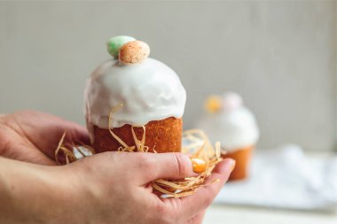 Paskalya arkaplanız kutlu olsun. Cilalı, çikolatalı ve küçük yumurtalarla süslenmiş paskalya pastası. Tebrik kartı, reklam, promosyon, poster, broşür, internet afişi, makale için resim. karmaşık kompozisyon, güzel manzara, hareket, eller