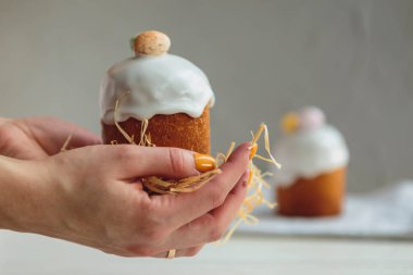 Paskalya arkaplanız kutlu olsun. Cilalı, çikolatalı ve küçük yumurtalarla süslenmiş paskalya pastası. Tebrik kartı, reklam, promosyon, poster, broşür, internet afişi, makale için resim. karmaşık kompozisyon, güzel manzara, hareket, eller