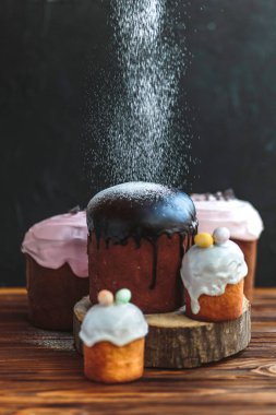 Paskalya arkaplanız kutlu olsun. Cilalı, çikolatalı ve küçük yumurtalarla süslenmiş paskalya pastası. Tebrik kartı, reklam, promosyon, poster, broşür, internet afişi, makale için resim. karmaşık kompozisyon, güzel manzara, hareket, eller