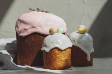 Paskalya arkaplanız kutlu olsun. Cilalı, çikolatalı ve küçük yumurtalarla süslenmiş paskalya pastası. Tebrik kartı, reklam, promosyon, poster, broşür, internet afişi, makale için resim. karmaşık kompozisyon, güzel manzara, hareket, eller