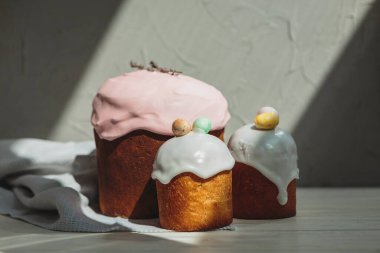 Paskalya arkaplanız kutlu olsun. Cilalı, çikolatalı ve küçük yumurtalarla süslenmiş paskalya pastası. Tebrik kartı, reklam, promosyon, poster, broşür, internet afişi, makale için resim. karmaşık kompozisyon, güzel manzara, hareket, eller