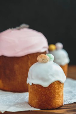 Paskalya arkaplanız kutlu olsun. Cilalı, çikolatalı ve küçük yumurtalarla süslenmiş paskalya pastası. Tebrik kartı, reklam, promosyon, poster, broşür, internet afişi, makale için resim. karmaşık kompozisyon, güzel manzara, hareket, eller