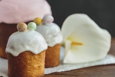 Paskalya arkaplanız kutlu olsun. Cilalı, çikolatalı ve küçük yumurtalarla süslenmiş paskalya pastası. Tebrik kartı, reklam, promosyon, poster, broşür, internet afişi, makale için resim. karmaşık kompozisyon, güzel manzara, hareket, eller