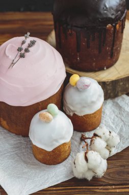 Paskalya arkaplanız kutlu olsun. Cilalı, çikolatalı ve küçük yumurtalarla süslenmiş paskalya pastası. Tebrik kartı, reklam, promosyon, poster, broşür, internet afişi, makale için resim. karmaşık kompozisyon, güzel manzara, hareket, eller