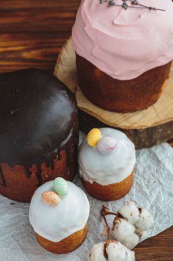 Paskalya arkaplanız kutlu olsun. Cilalı, çikolatalı ve küçük yumurtalarla süslenmiş paskalya pastası. Tebrik kartı, reklam, promosyon, poster, broşür, internet afişi, makale için resim. karmaşık kompozisyon, güzel manzara, hareket, eller