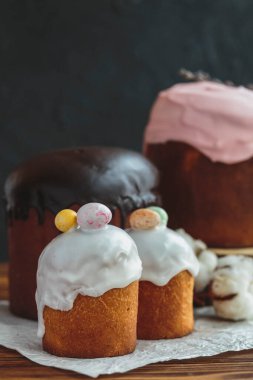 Paskalya arkaplanız kutlu olsun. Cilalı, çikolatalı ve küçük yumurtalarla süslenmiş paskalya pastası. Tebrik kartı, reklam, promosyon, poster, broşür, internet afişi, makale için resim. karmaşık kompozisyon, güzel manzara, hareket, eller