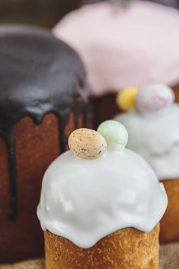 Paskalya arkaplanız kutlu olsun. Cilalı, çikolatalı ve küçük yumurtalarla süslenmiş paskalya pastası. Tebrik kartı, reklam, promosyon, poster, broşür, internet afişi, makale için resim. karmaşık kompozisyon, güzel manzara, hareket, eller