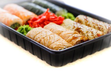 Suşi fotoğrafı ve siyah ayna arkaplanındaki roller.