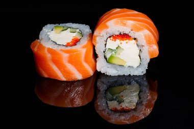 Suşi fotoğrafı ve siyah ayna arkaplanındaki roller.