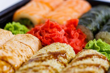 Suşi fotoğrafı ve siyah ayna arkaplanındaki roller.