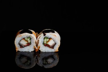 Suşi fotoğrafı ve siyah ayna arkaplanındaki roller.