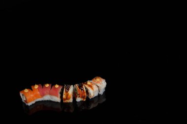 Suşi fotoğrafı ve siyah ayna arkaplanındaki roller.