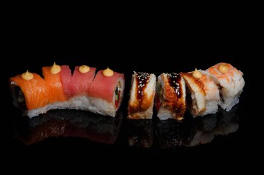 Suşi fotoğrafı ve siyah ayna arkaplanındaki roller.