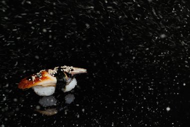 Siyah karlı zeminde gerçek suşi rulo Japon mutfağı. Noel 'de. Yeni Yıl.