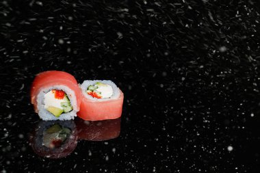 Siyah karlı zeminde gerçek suşi rulo Japon mutfağı. Noel 'de. Yeni Yıl.
