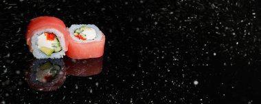 Siyah karlı zeminde gerçek suşi rulo Japon mutfağı. Noel 'de. Yeni Yıl.